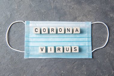 Harfli mavi tek kullanımlık yüz maskesi ve Corona virüsü, üst görünüm, sağlık konsepti.