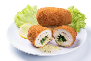 Tavuklu Kiev pirzolası, yeşil salata ve limon dilimli, beyaz arka planda.
