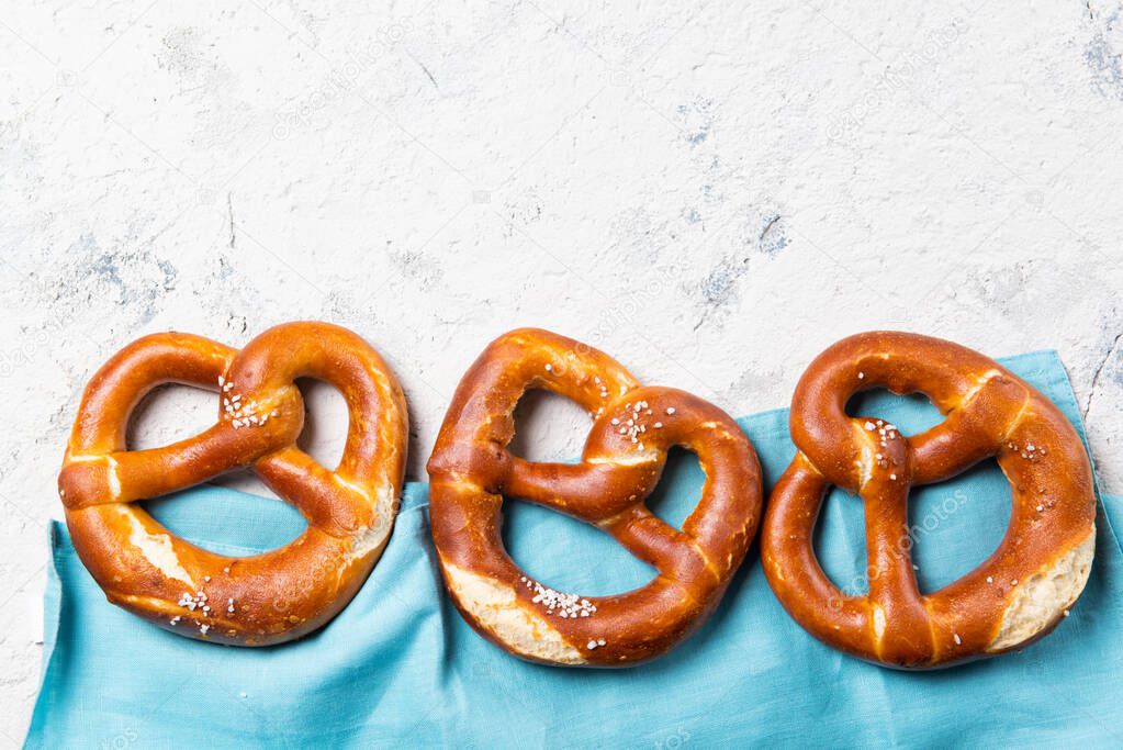 Fresh backed pretzels in a row on a blue towel, beer snack, top view with copy space