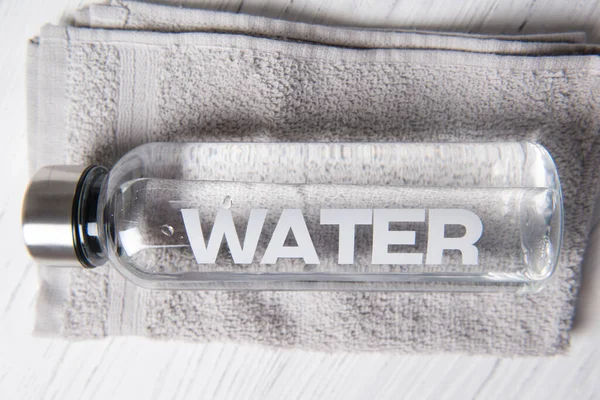 Botol Air Dengan Air Kata Atasnya Pada Handuk Abu Abu — Stok Foto
