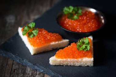 Kırmızı havyarlı aperatifler koyu arka planda, seçici odaklı.