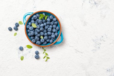 Taze olgun yaban mersinleri ve taş bir masada yapraklar, fotokopi alanı ile üst manzara.