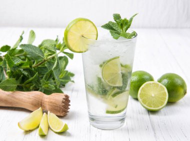 Taze limonlu mojito kokteyli ve açık ahşap arka planda bir bardakta nane yaprağı.