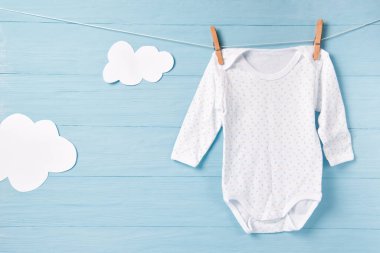 Bebek kıyafetleri ve beyaz bulutlar çamaşır ipinde, mavi arkaplan