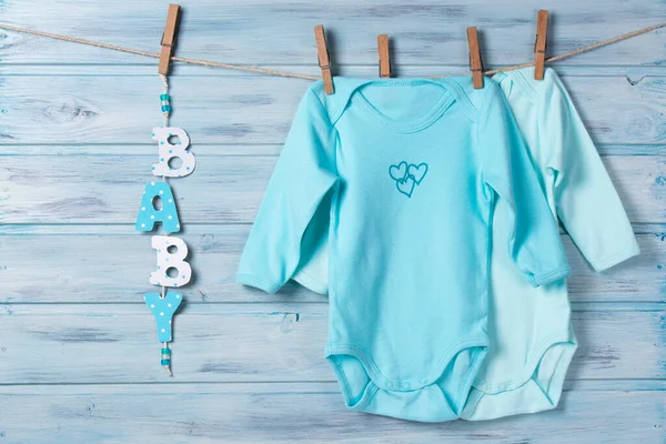 Babykleertjes Woordbaby Een Waslijn Blauwe Houten Achtergrond — Stockfoto