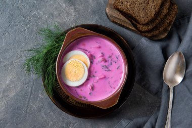 Soğuk pancar çorbası kefir ile servis edilen haşlanmış yumurta, dereotu ve ekmek dilimleri, kırsal arka plan, üst manzara