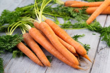 Tahta zemin üzerinde yeşillikler olan taze havuçlar.