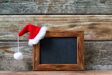 Mutlu Noeller boş tahta tahta, ahşap arka planda kırmızı bir Noel Baba şapkası