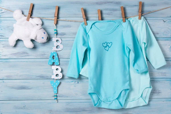 Babykleertjes Witte Speelgoedbeer Woordbaby Een Waslijn Blauwe Houten Achtergrond — Stockfoto