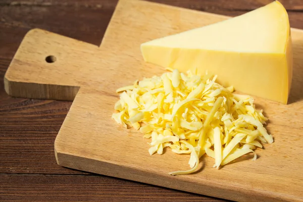 Grated cheese and cheese triangle on wooden table