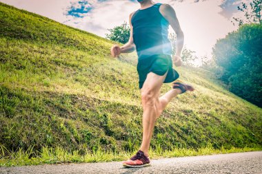 Gün batımında triatlonda koşan atletik bir adam.