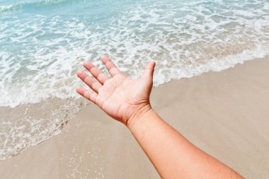 El, denizde beyaz kumu tutuyor..