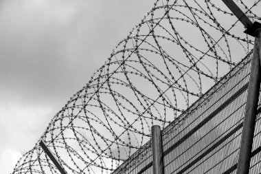 Bulutlu gökyüzü karşı dikenli tel çit