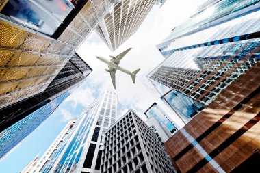 Şehirdeki modern gökdelenlerin üzerinde uçan uçak