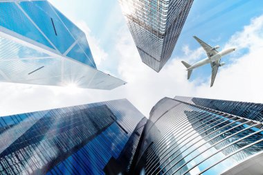 Şehirdeki modern gökdelenlerin üzerinde uçan uçak