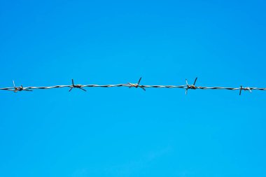Mavi gökyüzüne karşı dikenli tel