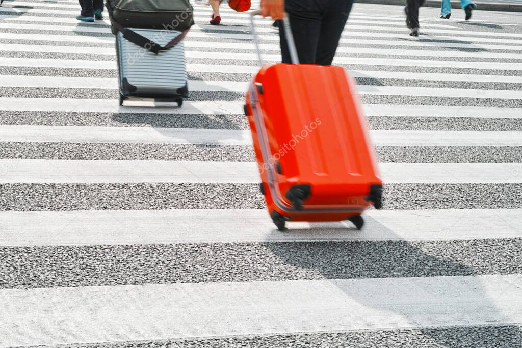 People with suitcases crossing road 