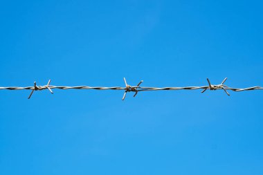 Mavi gökyüzü arka planında dikenli tel