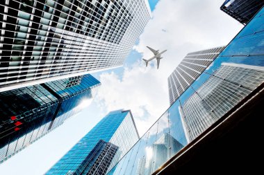 Şehirdeki modern gökdelenlerin üzerinde uçan uçak