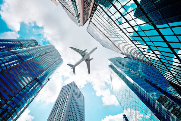 Airplane flying over modern skyscrapers in city