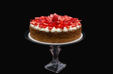 Çilek süslemeli, siyah arka planlı Mostachon adında lezzetli bir pasta.