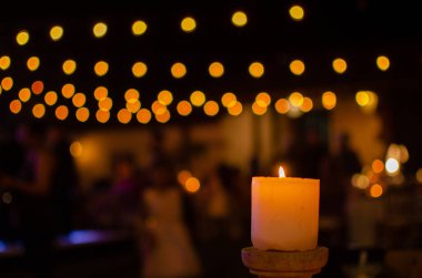 Ön planda mum ve arka planda ışıklar. Parti atmosferi, dekorasyon.