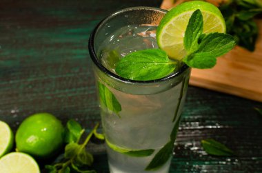 Mojito, Küba kaynaklı kokteyl, yeşil bir masada kokteyl malzemeleriyle süslenmiş. Ahşap arkaplan.
