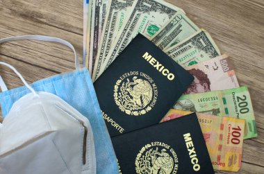 Maskeler, Meksika pasaportları ve para, tahta bir masanın üzerinde. Amerikan Doları ve Meksika Pezosu.