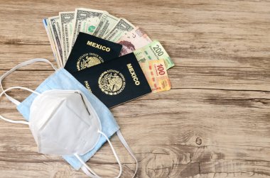 Maskeler, Meksika pasaportları ve para, tahta bir masanın üzerinde. Amerikan Doları ve Meksika Pezosu.