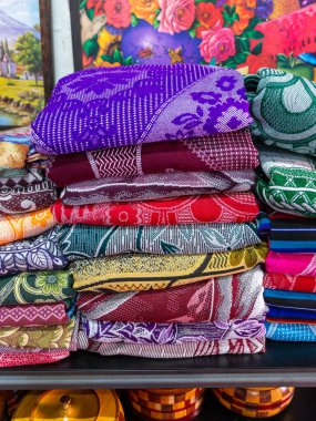 Renkli, karmaşık dokuma ürünlerinin düzgünce dizilmiş bir görüntüsü canlı desenler ve dokular sergiliyor..