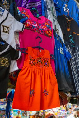 Turuncu bir elbise ve çocuk gömleği de dahil olmak üzere parlak renkli nakışlı bir elbise.