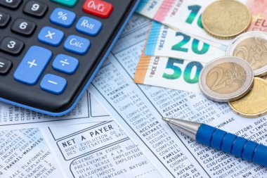 Fransa 'da Ocak 2019' dan beri zorunlu olan sosyal katkı payı ve gelir vergisi indirimi ile birlikte bir hesap makinesi, bir kalem, bir avro sikke ve banknotları ile birlikte Fransız maaşları.