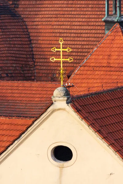 Christian cross above red tiles roofs, Mala Strana, Prague, Czech republic