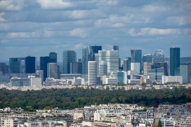 La Defense 'ın hava manzarası, Paris' in iş bölgesi, bulutlu gökyüzü, Paris binaları ve ön plandaki Bois de Boulogne.