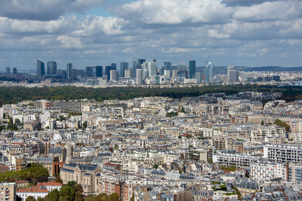 Aerial view of the towers of La Defense, business district of Paris, France, sunny with cloudy sky, parisian buildings and the bois de Boulogne in the foreground