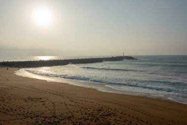 Gün batımı, Atlantik okyanusu dalgaları ve birkaç sörfçü. La Barre Plajı, Anglet, Fransa