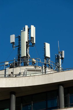 Bir binanın çatısına 5G ve 4G cep telefonu anteni yerleştirilmiş. Mavi gökyüzü