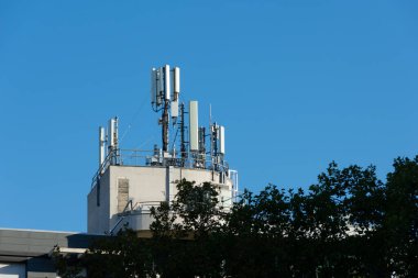 Bir binanın çatısına 5G ve 4G cep telefonu anteni yerleştirilmiş. Mavi gökyüzü
