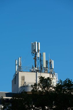 Bir binanın çatısına 5G ve 4G cep telefonu anteni yerleştirilmiş. Mavi gökyüzü