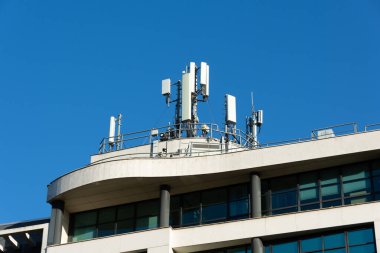 Bir binanın çatısına 5G ve 4G cep telefonu anteni yerleştirilmiş. Mavi gökyüzü