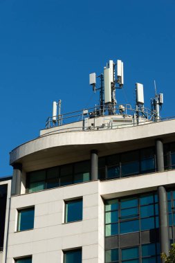 Bir binanın çatısına 5G ve 4G cep telefonu anteni yerleştirilmiş. Mavi gökyüzü