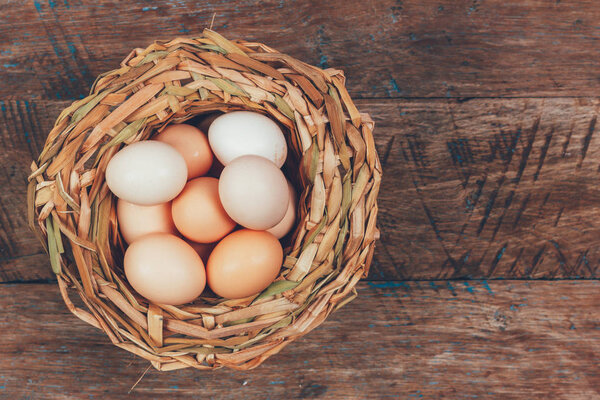 eggs from domestic chickens in wicker basket on wooden retro grunge background with copy space