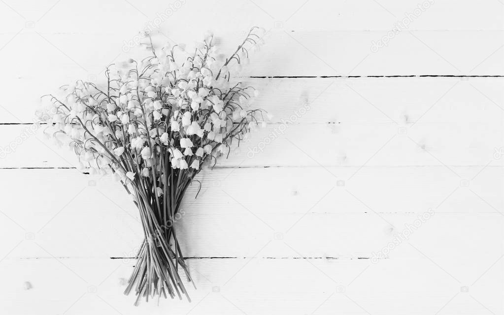 bouquet of lilies of the valley flowers closeup on white wooden table with copy space, black and white photo