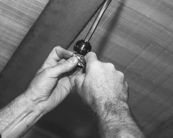 man electrician installs an electric lamp holder, black and white photo