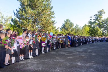 Adıge, Rusya - 1 Eylül 2017: okul öğretmen ve öğrencilerin bilgi gün öğretim yılı ciddi bir cetvel üzerinde birinci sınıfta kayıtlı çiçek demetleri çocuklarla