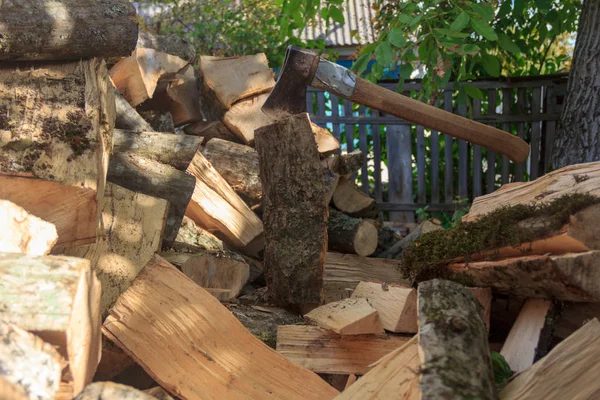 一堆木头和一把斧头卡在树桩里 — 图库照片