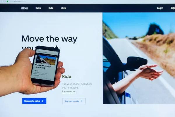 モスクワ ロシア連邦 2018 インターネットのホームページ画面上のモバイル アプリケーション Uber Com の男性のスマート フォンに手を背景のモニターに対して — ストック写真