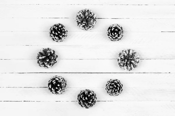 Christmas wreath of pine cones on a white wooden background. Flat lay, top view, copy space, black and white photo