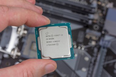 Maykop, Rusya - 9 Kasım 2018: Intel core I3 masaüstü işlemci 8 gen arka plan anakart closeup üstten görünüm üzerinde parmak tutan adam