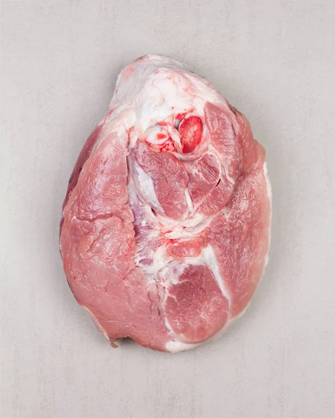 large piece of pork meat with bone on grey background close up, top view